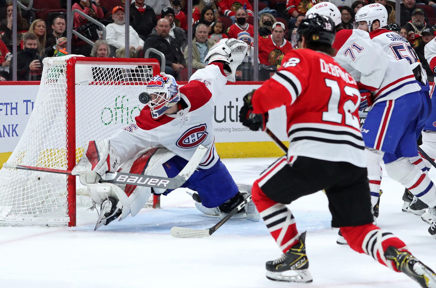 Montreal Canadiens goaltender Sam Montembeault (35) deflects a shot on goal by Chicago Blackhawks left wing Alex DeBrincat (12) in the third period at United Center on Jan. 13, 2022, in Chicago.