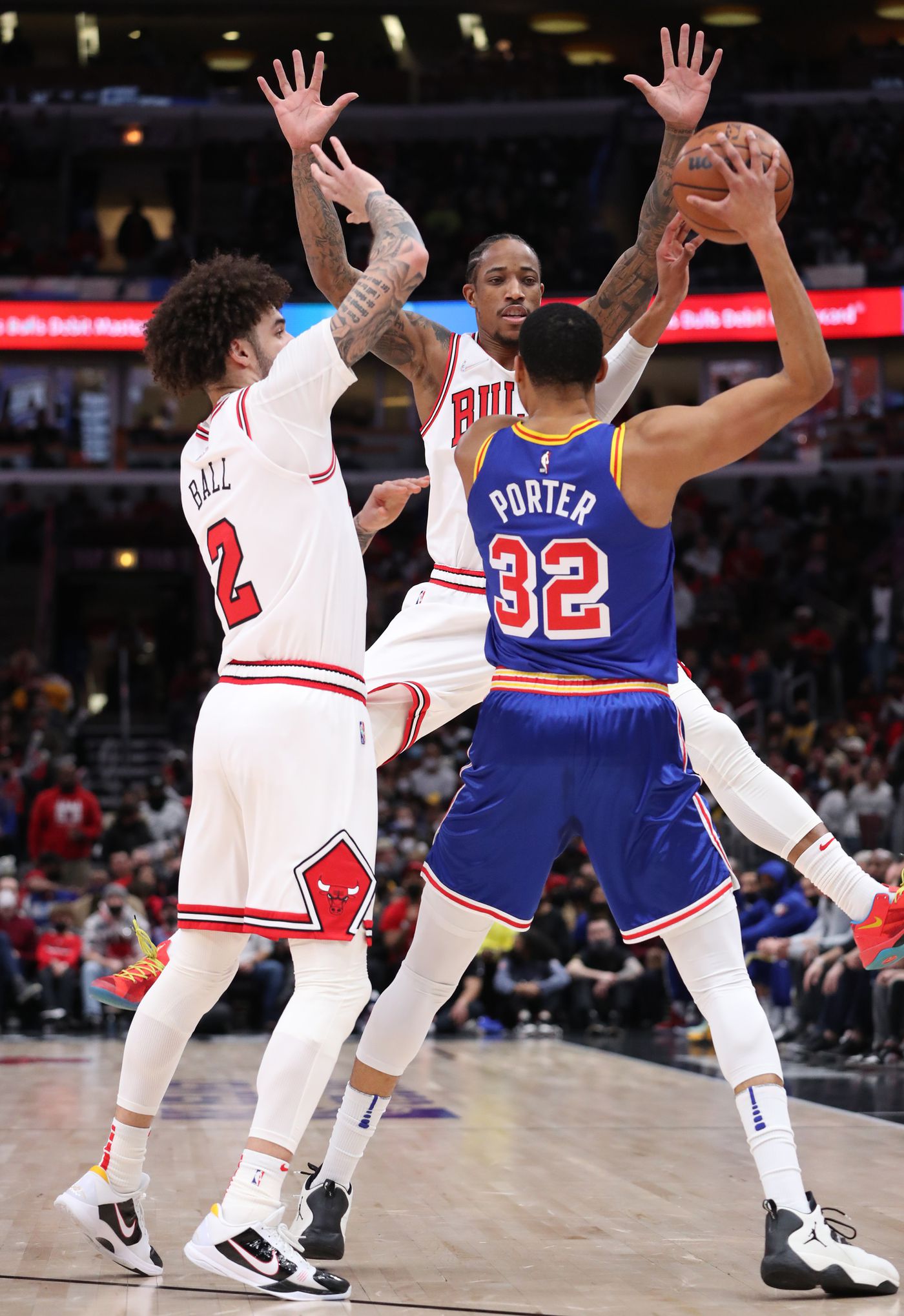 Chicago Bulls guard Lonzo Ball (2) and forward DeMar DeRozan (11) defend Golden State Warriors forward Andrew Wiggins (22) in the first quarter at United Center on Jan. 14, 2022, in Chicago.