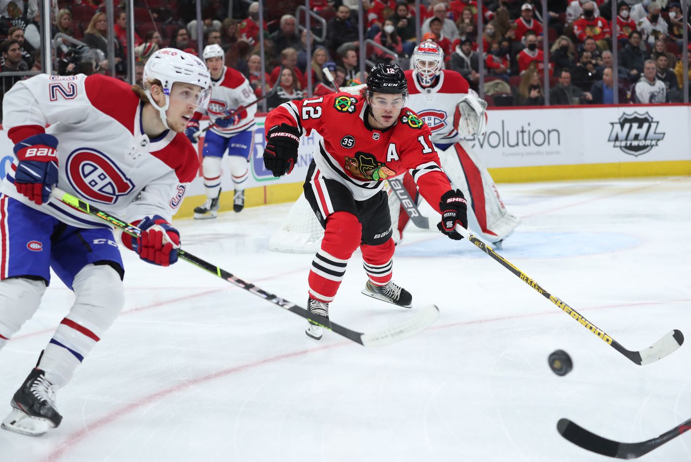 Chicago Blackhawks left wing Alex DeBrincat (12) stretches to reach for the puck in the first period against the Montreal Canadiens at United Center on Jan. 13, 2022, in Chicago.