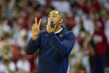 Michigan coach Juwan Howard strikes a Wisconsin assistant during a postgame argument, setting off a skirmish