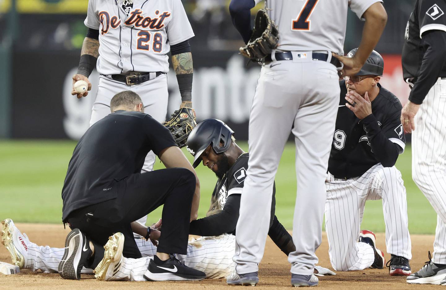 A White Sox trainer checks on the left wrist area of center fielder Luis Robert after Robert attempted to steal second base in the sixth inning against the Tigers on Aug. 12 at Guaranteed Rate Field. 