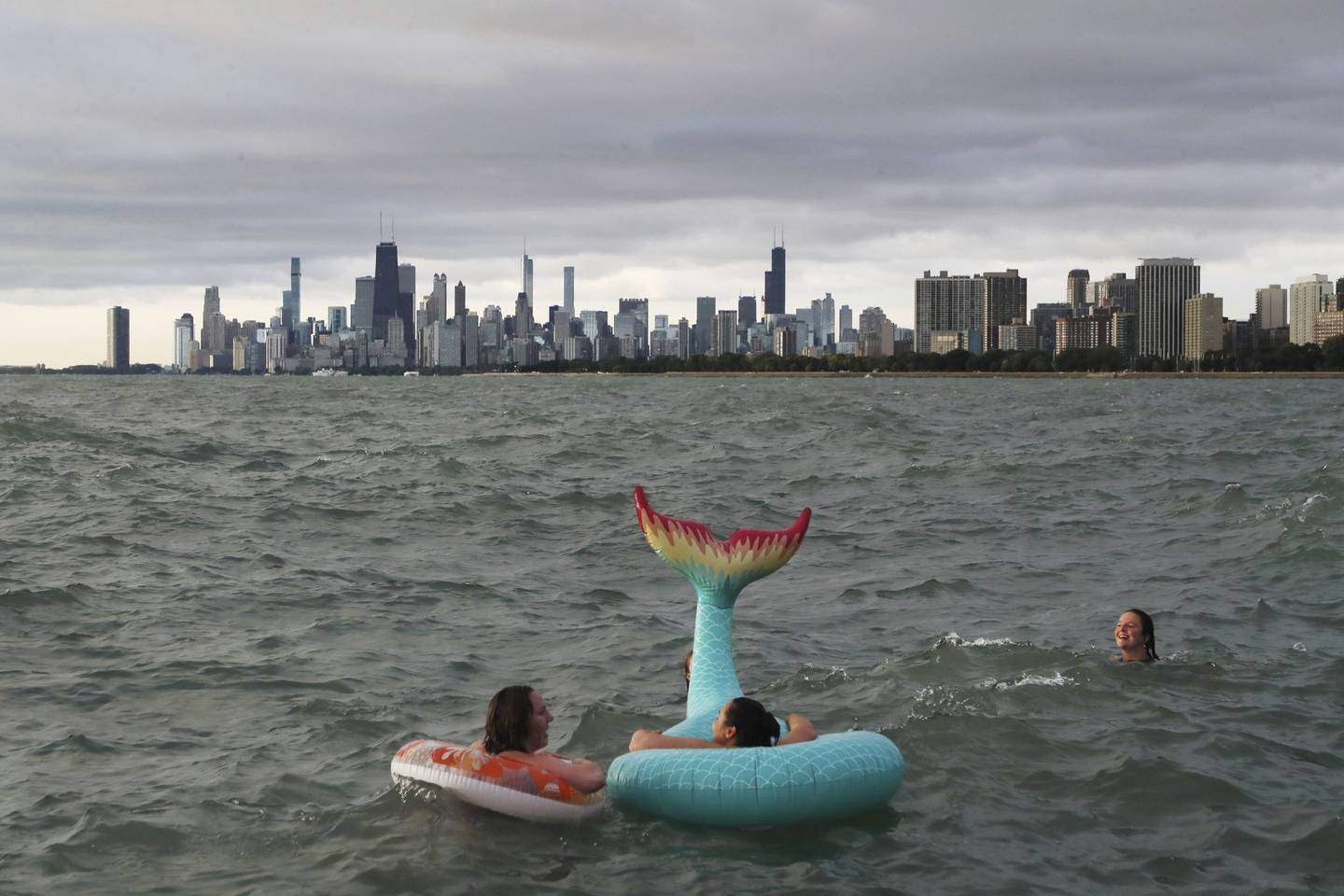 Lauren Anderson, left, and Gloria Janek, center, take in the high waves and skyline while floating in Lake Michigan as part of the Friday Morning Swim Club at Montrose Harbor.