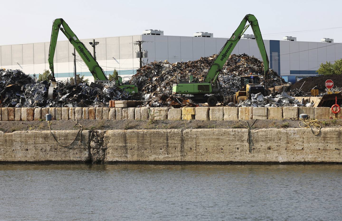 Mounds of scrap metal are moved at the Sims Metal recycling company, across the South Branch of the Chicago River from the Canalport Riverwalk on Sept. 16, 2022.