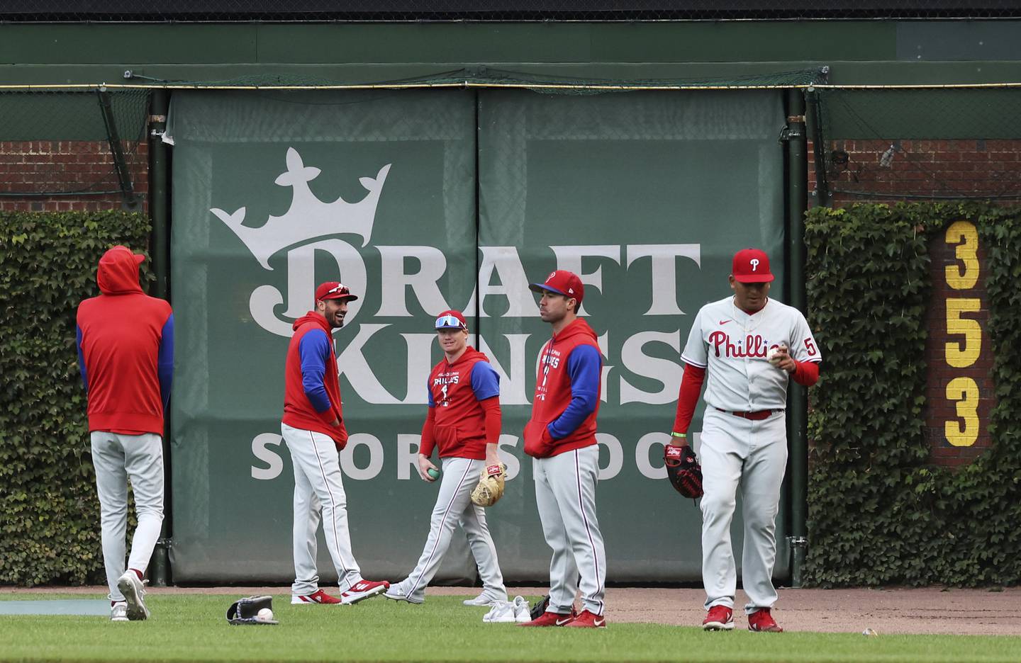 A DraftKings Sportsbook logo is displayed on the right field wall of Wrigley Field as Philadelphia Phillies players warm up for a game against the Chicago Cubs on Sept. 27, 2022.