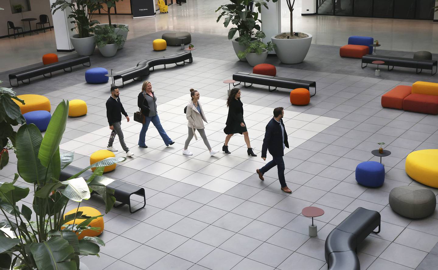 People walk through the central square at Bell Works Chicagoland in Hoffman Estates. The square is a tall, airy space decorated with brightly colored Italian furniture. 