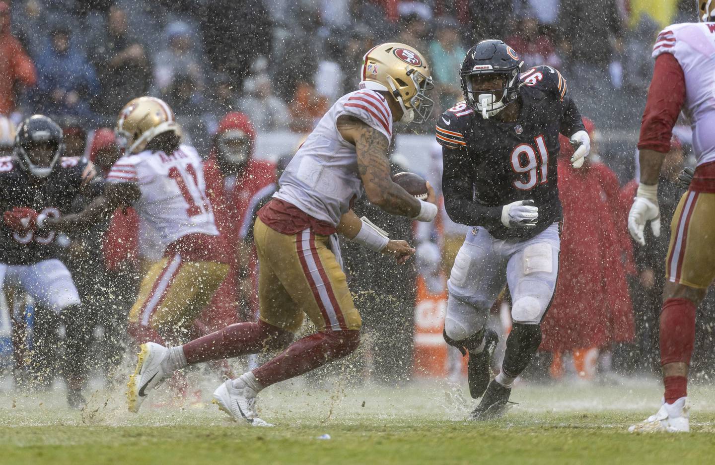 Bears defensive end Dominique Robinson (91) chases down 49ers quarterback Trey Lance (5) in the rain on Sept. 11, 2022, at Soldier Field.