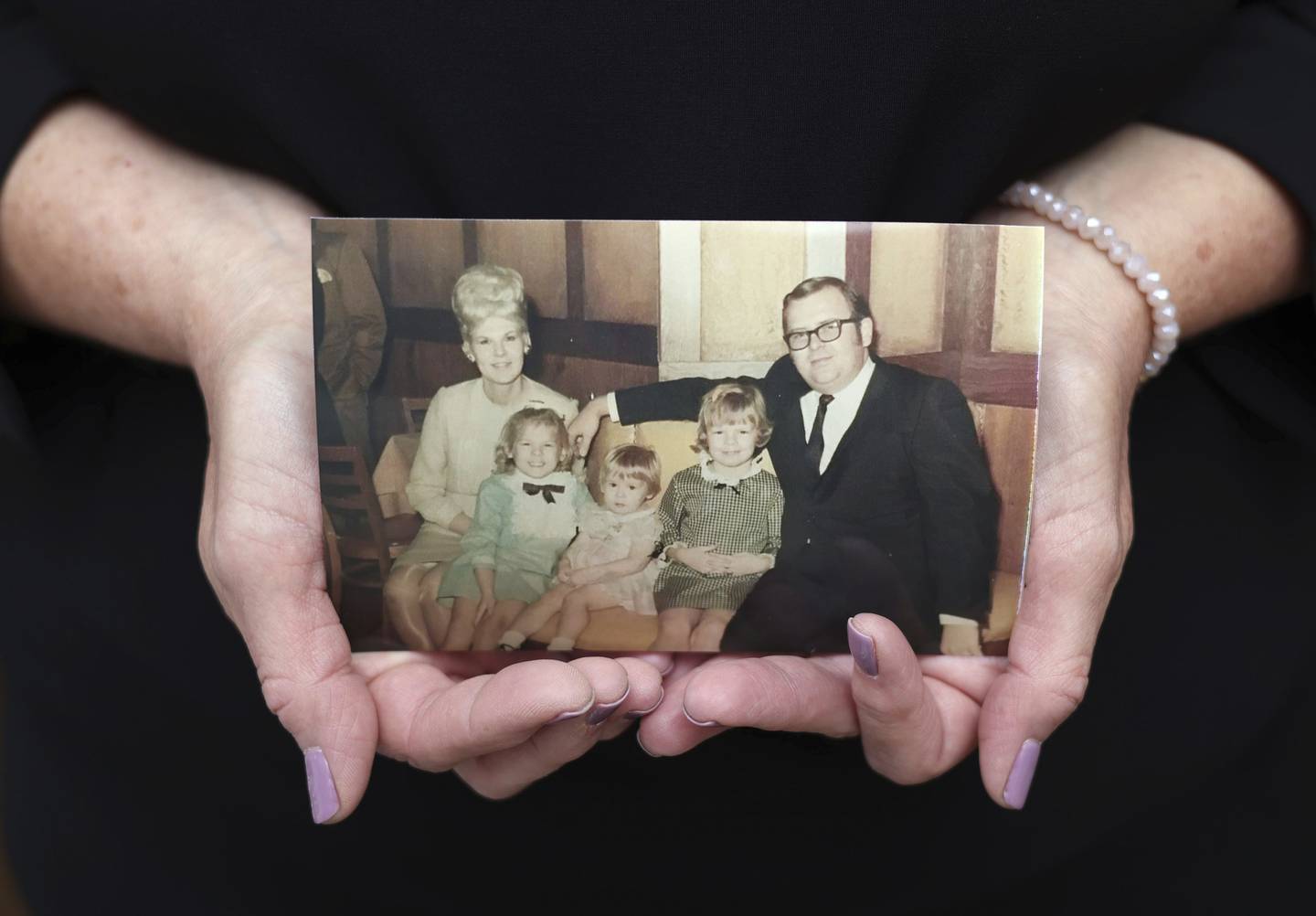 Laurie Edling holds a family photo from 1968 showing her parents, Loretta and John Stanisha, along with their three children: Therese, 6, Laurie, 2, and Susan, 7.