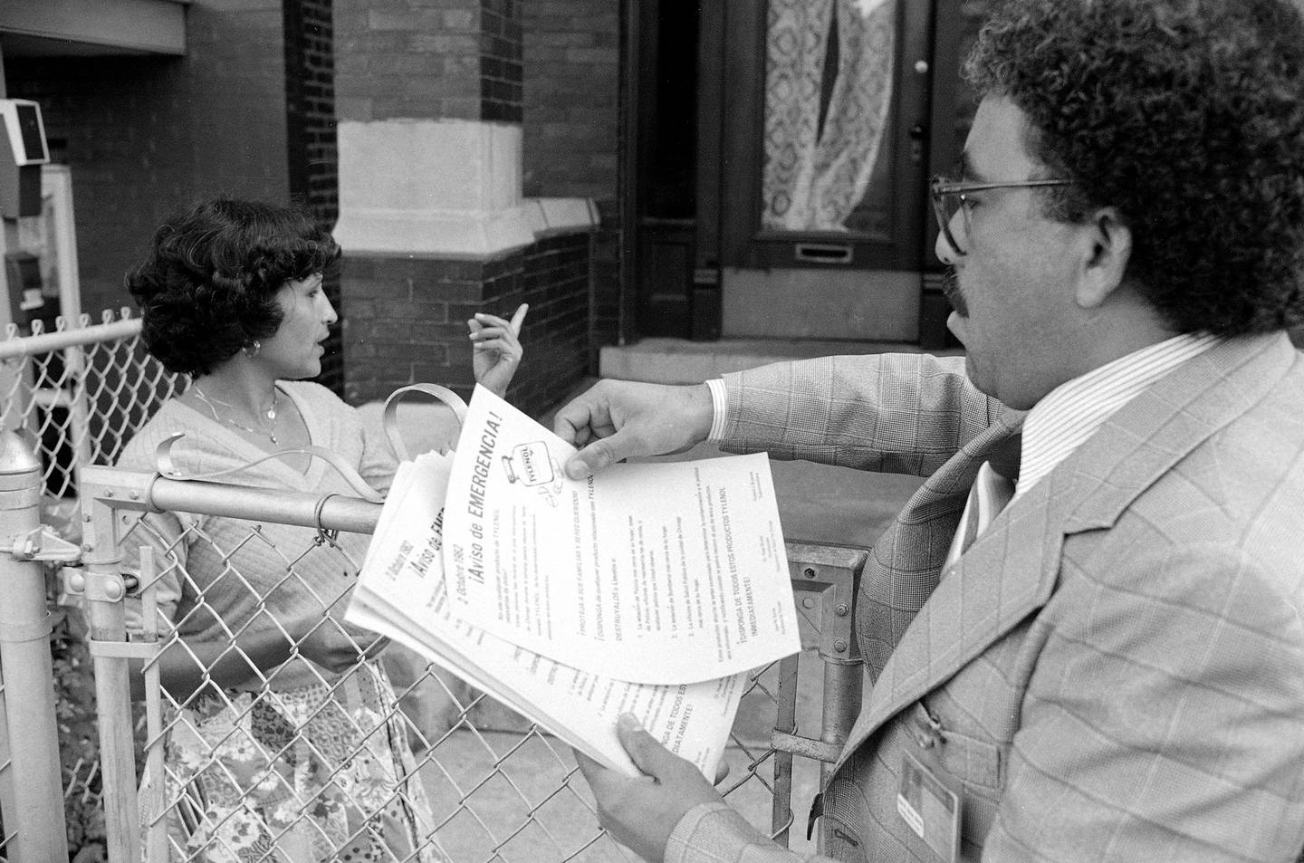Jose Rosa, right, was one of hundreds of Chicago city employees and volunteers to distribute warnings about cyanide-laced Tylenol in fall 1982. Here, he offers a Spanish-language flyer to Luisa Acevada.