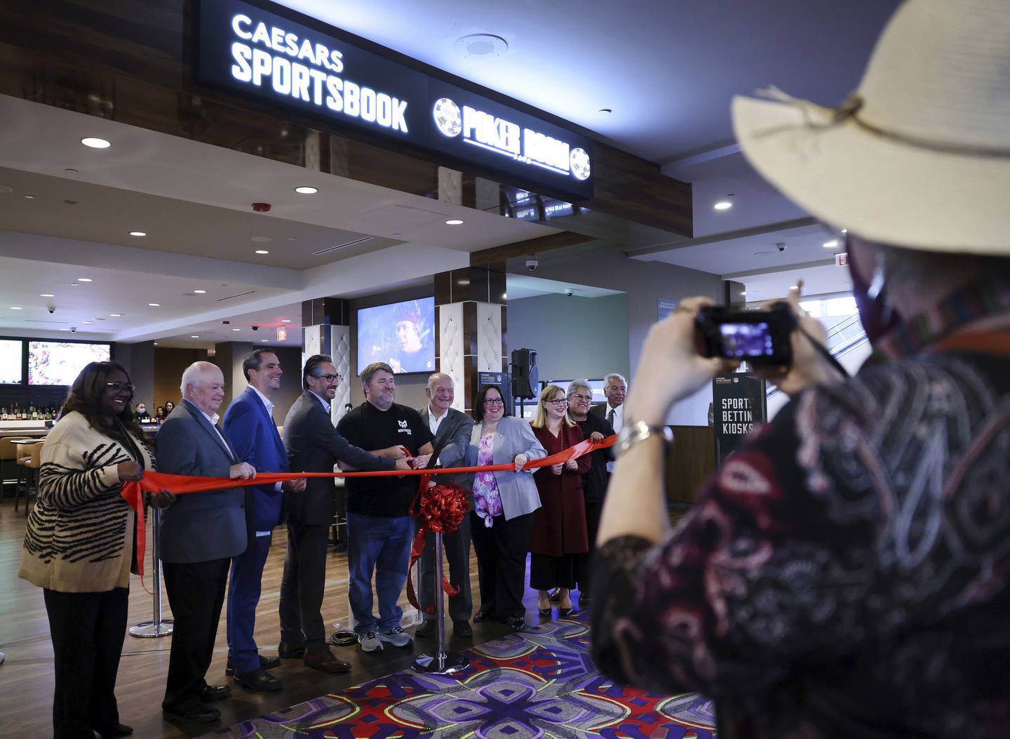 Professional poker player Chris Moneymaker, fifth from left, with dignitaries before cutting the ribbon to celebrate the opening of the new Caesars Sportsbook and poker room at Grand Victoria Casino in Elgin on Oct. 20, 2022. 