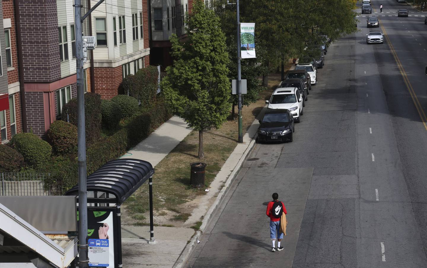 A person stands on the street hoping to spot a CTA #4 Cottage Grove bus at 63rd Street in Chicago on Oct. 6, 2022.   