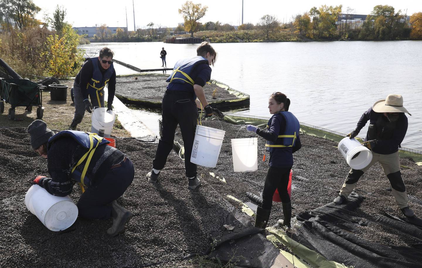 A group of volunteers load up several buckets of substrate before adding plants on the floating wetlands.