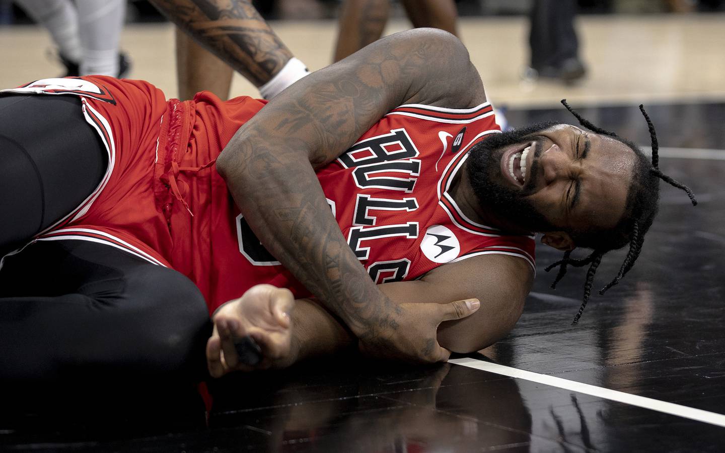 Bulls center Andre Drummond grabs his left arm after crashing to the court during the second half against the Spurs on Friday in San Antonio. Drummond sprained his left shoulder on the play and sat out Saturday against the 76ers. 