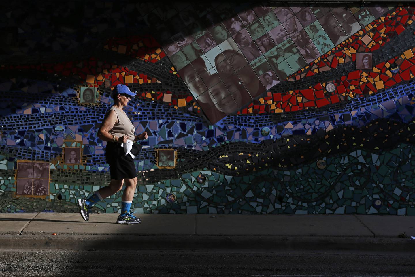 A runner passes by a mural called "Indian Land Dancing" at Foster Avenue and Lake Shore Drive in Chicago on Aug. 6, 2015. 