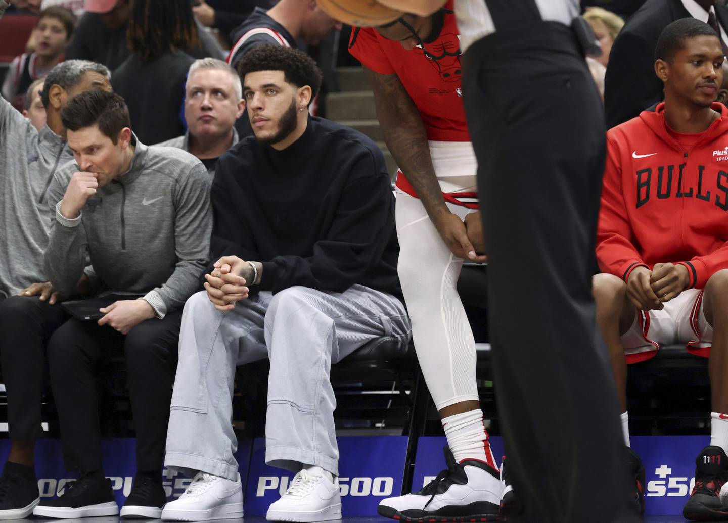 Bulls guard Lonzo Ball, wearing blue jeans, sits on the bench during a game against the Cavaliers on Oct. 22, 2022, at the United Center. 