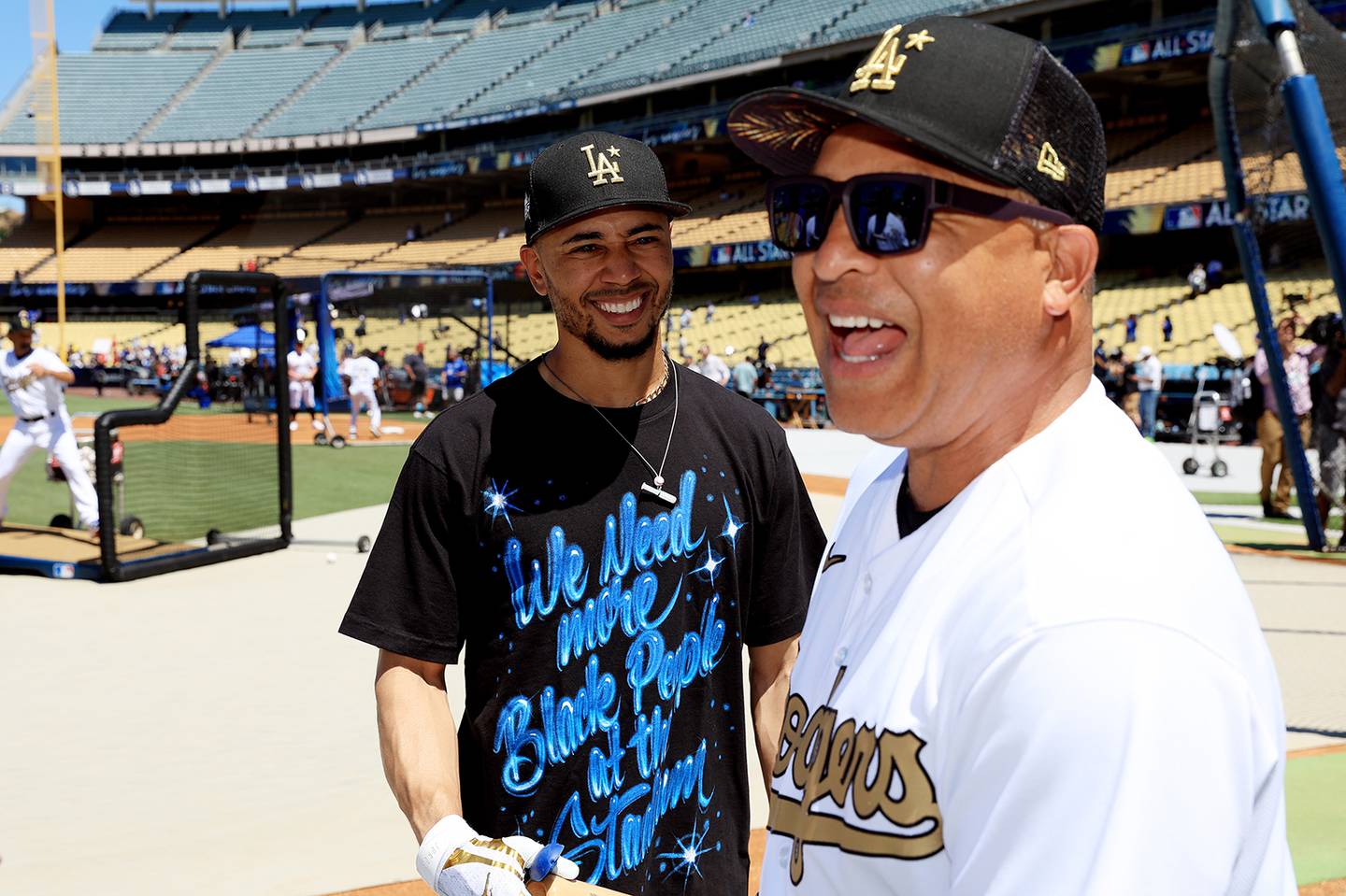 Dodgers outfielder Mookie Betts talks with manager Dave Roberts during batting practice for the All-Star Game on July 19, 2022, at Dodger Stadium in Los Angeles. Betts wore a T-shirt over his uniform that read “We Need more Black People at the Stadium.” 