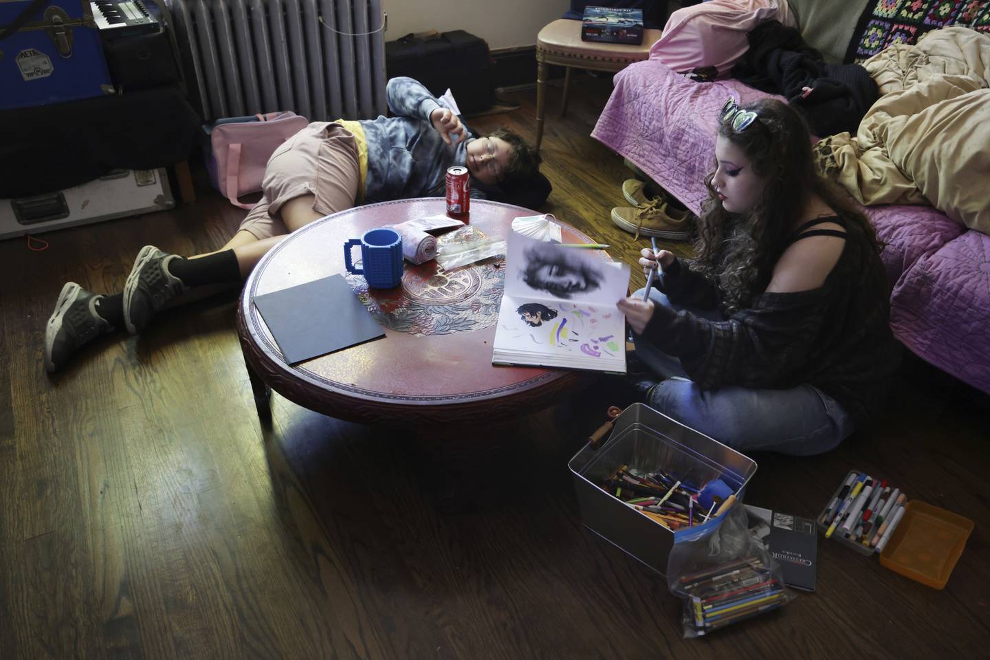 Nehemiah Mejia, 11, left, and his sibling Lourdes Mejia, right, 15, relax in the Chicago home of a family friend on Sept. 30, 2022. The Mejia family, including their mother and another sibling, was displaced from Florida by Hurricane Ian. Lourdes is drawing with donated art supplies. 