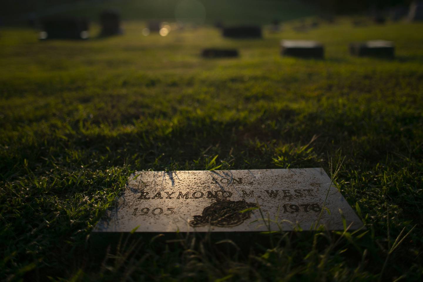 The sun rises over the grave of Raymond West, who is buried in Oak Hill Cemetery in Carrollton, Missouri. James Lewis has long denied killing West, who died in 1978.