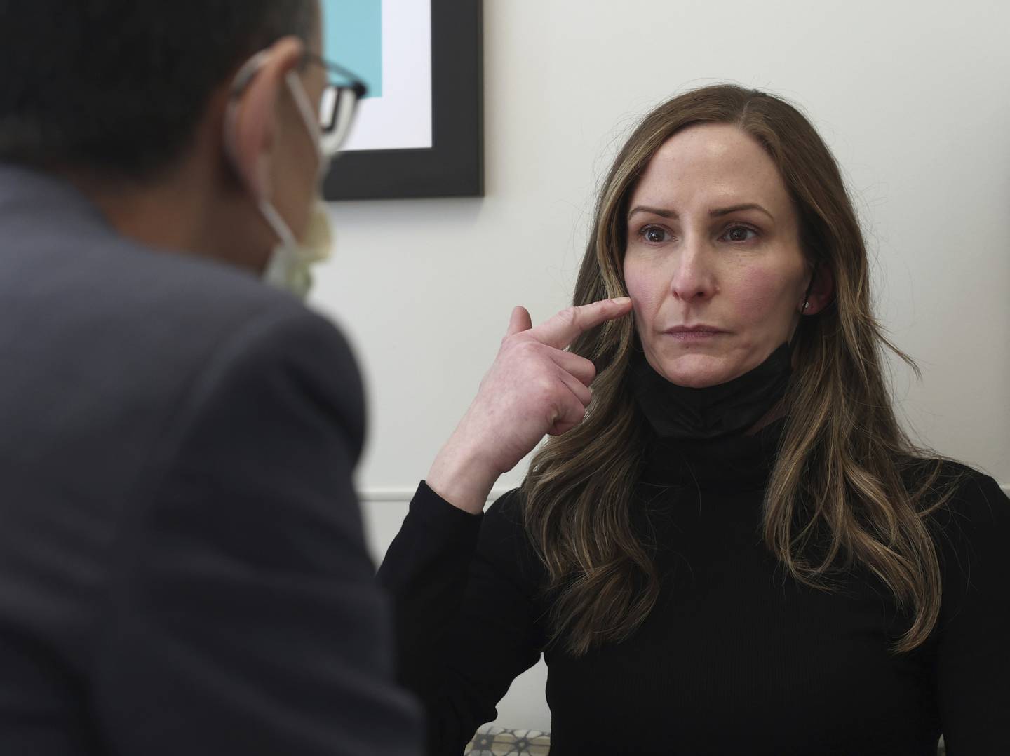 Amy Tomasulo points out the parts of her face that cause severe pain in certain situations during an appointment with Dr. Babak Jahromi at Northwestern Memorial Hospital on Oct. 20, 2022. Tomasulo has a rare disease called trigeminal neuralgia, which causes severe, chronic pain in the face and neck.  
