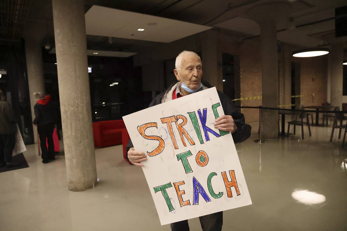 George Otto, 93, a retired professor, holds up a sign during a Thursday rally for City Colleges of Chicago faculty and professional staff, who have set a strike date for next week.  