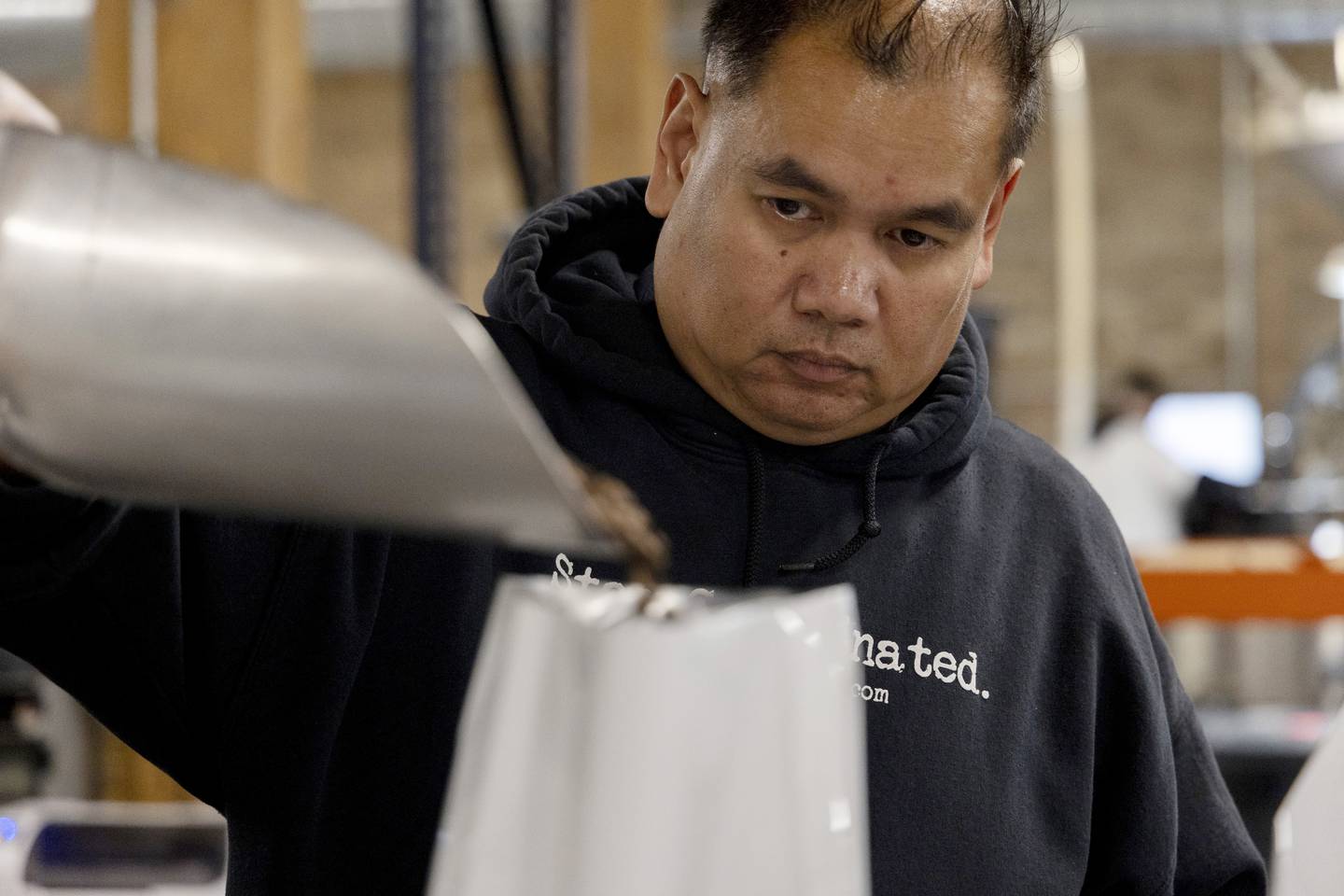 Veteran Roasters employee Jessie Avecilla (cq), who is a Navy veteran, fills a bag with coffee beans on Oct. 3, 2022.