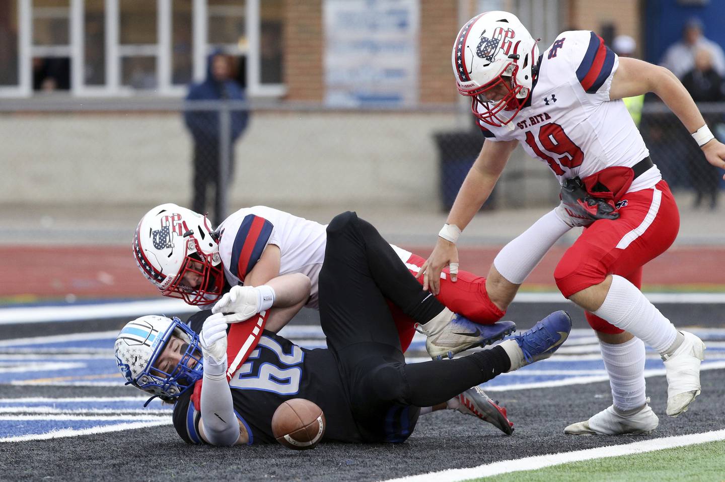 St. Rita's Noah Gertonson (19) jumps on the ball for a touchdown while teammate Johnny Schmidt tackles St. Charles North's Cole Schertz (62) during a Class 7A state quarterfinal game in St. Charles on Saturday, Nov. 12, 2022.
