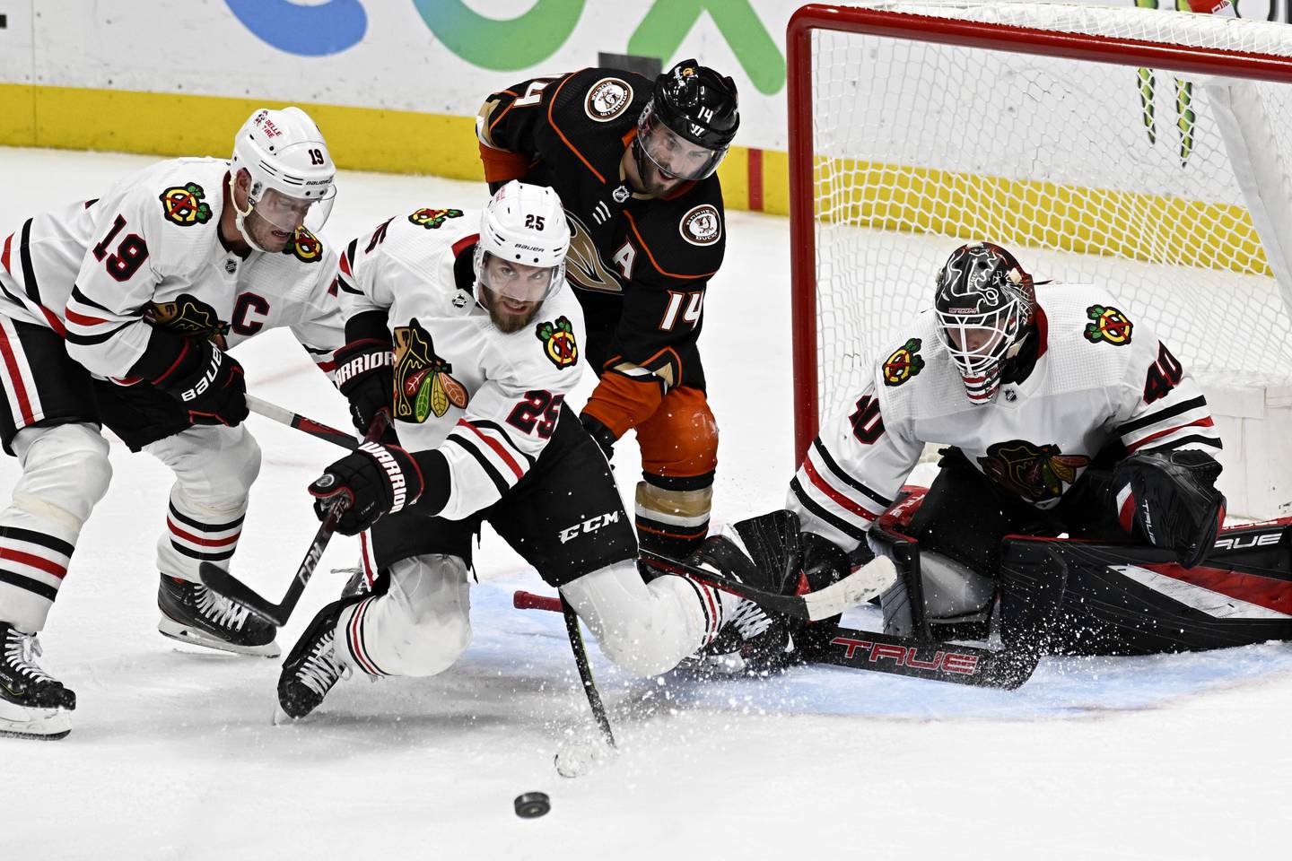 Blackhawks defenseman Jarred Tinordi clears the puck away from Ducks center Adam Henrique with goaltender Arvid Soderblom and center Jonathan Toews defending during the third period on Nov. 12, 2022.