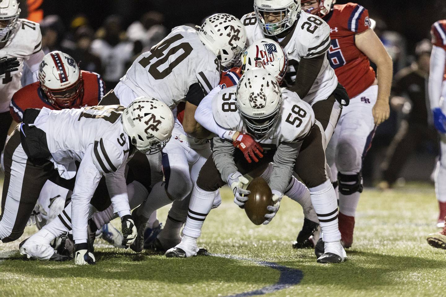 Mount Carmel's Bobby Medina (58) scoops up a St. Rita fumble during a Class 7A state semifinal game in Chicago on Saturday, Nov. 19, 2022.
