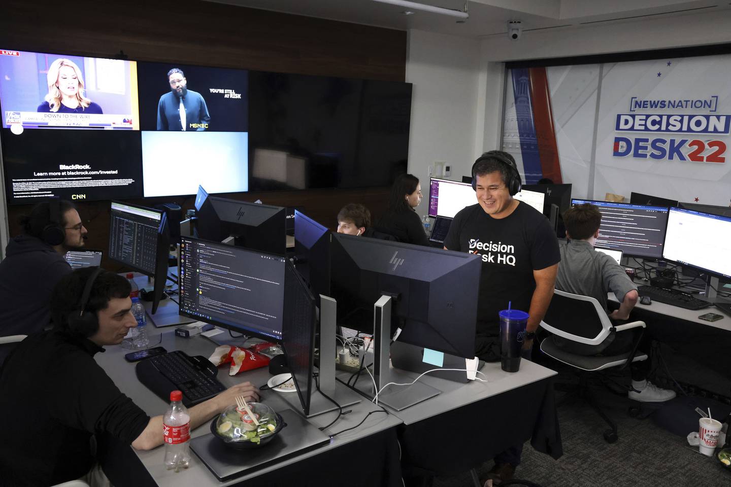 Scott Tranter, standing at right, director of data science for the cable station NewsNation’s election night “Decision Desk,” which tracks results, is seen in the newsroom in Chicago on Nov. 7, 2022.  