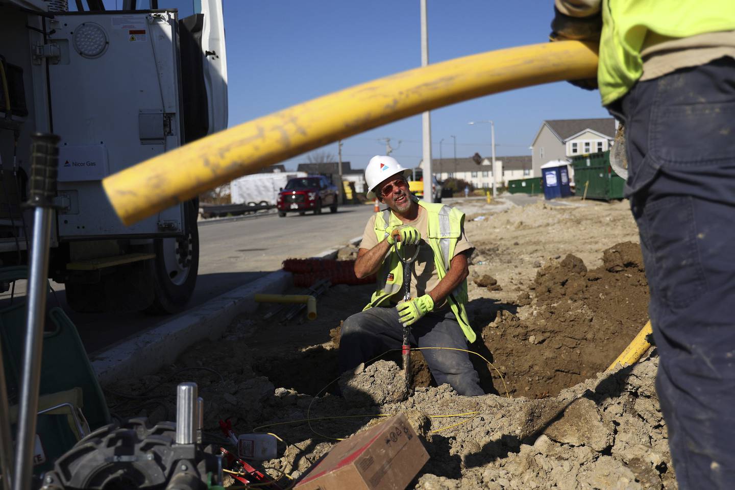 Nicor worker Dylan Klatt, right, holds a gas line as Larry Voight, left, digs a trench to place it underground at a new subdivision in Aurora on Nov. 2, 2022.