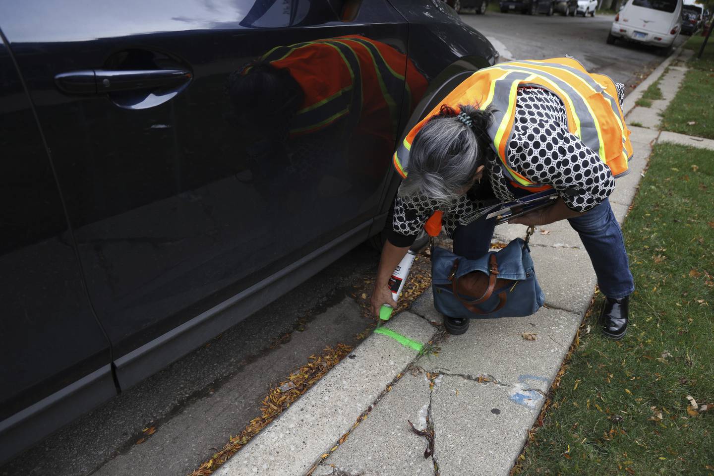 Volunteer Dulce Garduno spray-paints the sidewalk a location for a potential future tree on a block in Little Village on Oct 13, 2022.