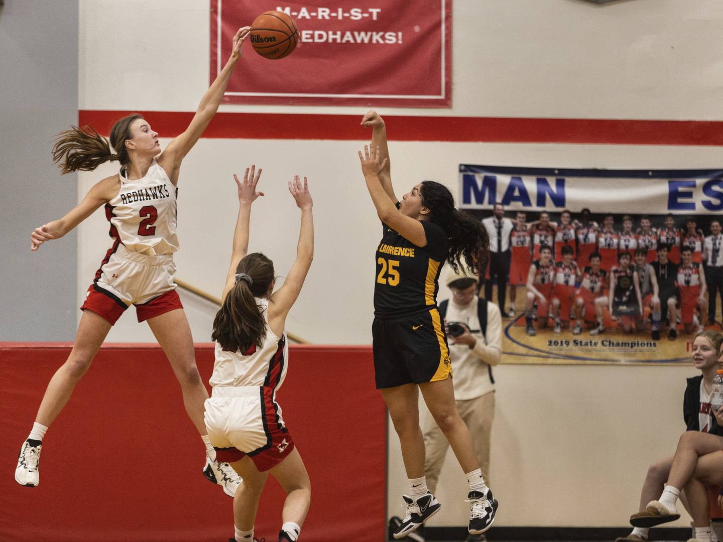 Marist’s Elise Ward (2) blocks a 3-point shot by St. Laurence's Lilliana Magana (25) during a nonconference game in Chicago on Monday, Dec. 19, 2022.