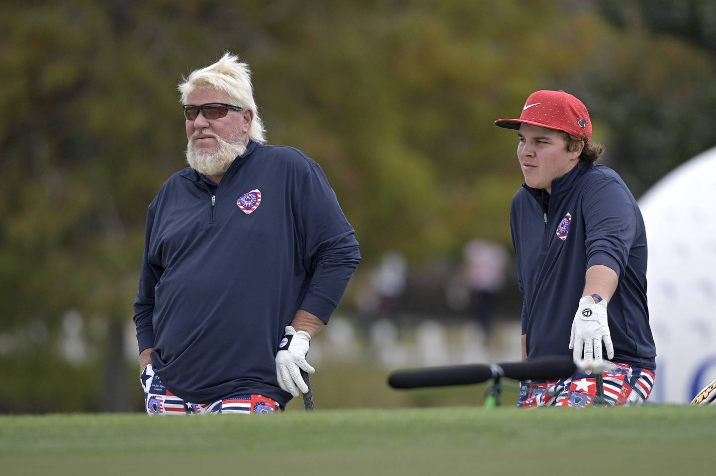 John Daly, left, and his son Little John Daly wait to hit from a bunker at the 18th green during the 2020 PNC Father-Son Challenge. 