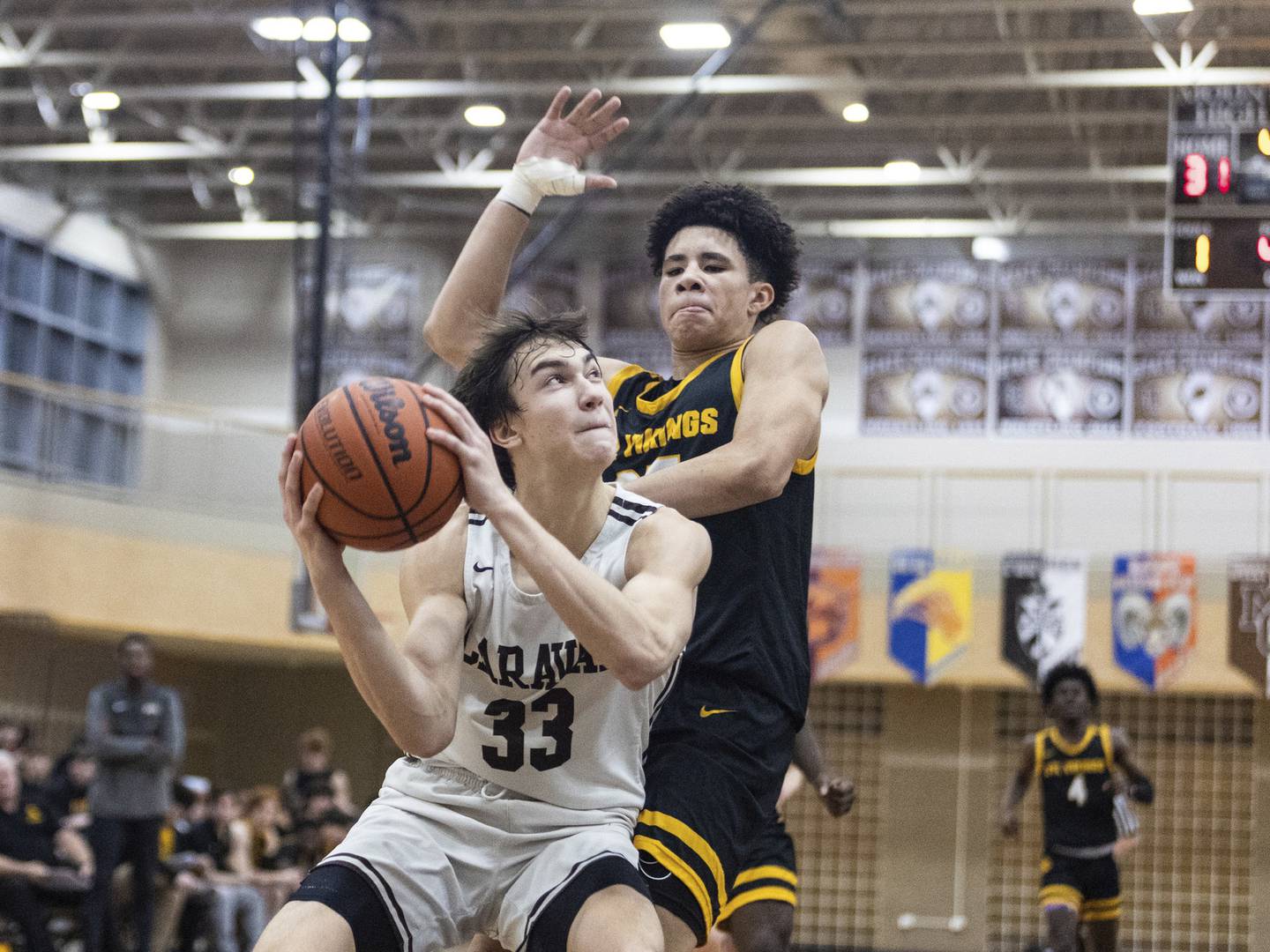 Mount Carmel's Angelo Ciaravino (33) drives to the basket as St. Laurence's Jacob Rice defends during a Catholic League crossover in Chicago on Tuesday, Dec. 6, 2022.