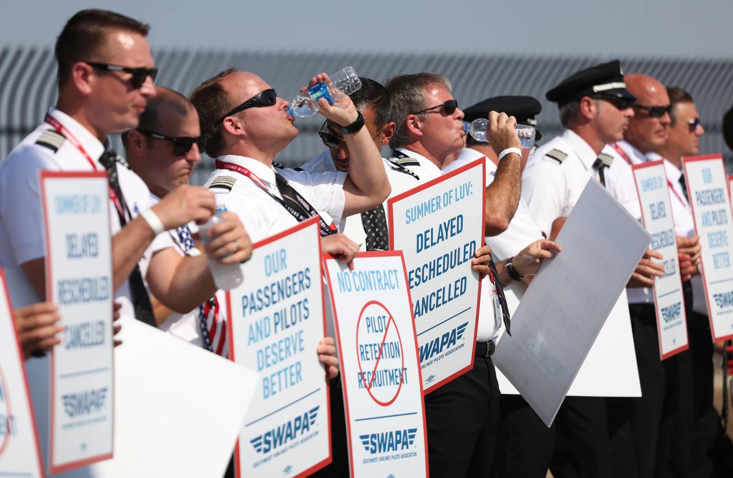 Southwest Airlines pilots drink water while picketing for better work conditions on June 21, 2022, outside Dallas Love Field.