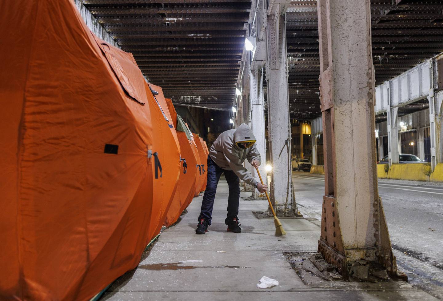 Shawn Scott sweeps the sidewalk on North Milwaukee Avenue near Fulton Market on Dec. 20, 2022. Scott says once a week he cleans the entire sidewalk outside his and others' winterized tents on Milwaukee Avenue.  