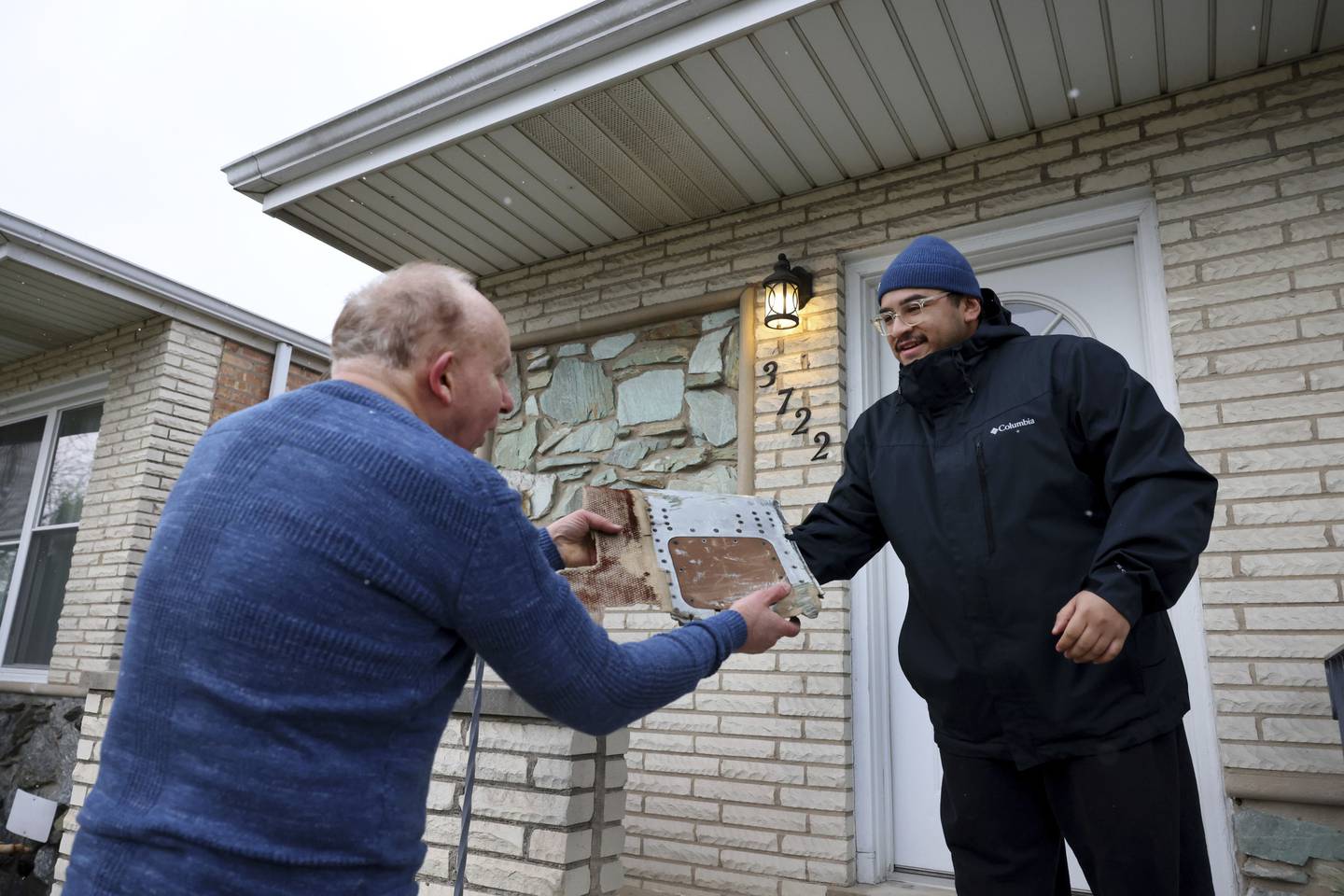 Survivor Evan Cotter Jr., left, shows neighbor Antonio Garcia, 30, a piece of the United Airlines 737 plane that crashed in Chicago’s West Lawn neighborhood on Dec. 8, 1972. Cotter was home in 1972 when the wing of a Boeing 737 slammed into the back of his family’s house. Garcia lives in the rebuilt home where the Boeing 737 crashed.