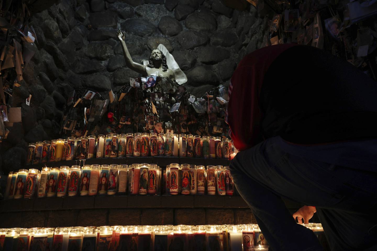 Roberto Fuentes arranges a candle at an altar at the Shrine of Our Lady of Guadalupe after a truck caravan arrived on Dec. 3, 2022, in Des Plaines. 