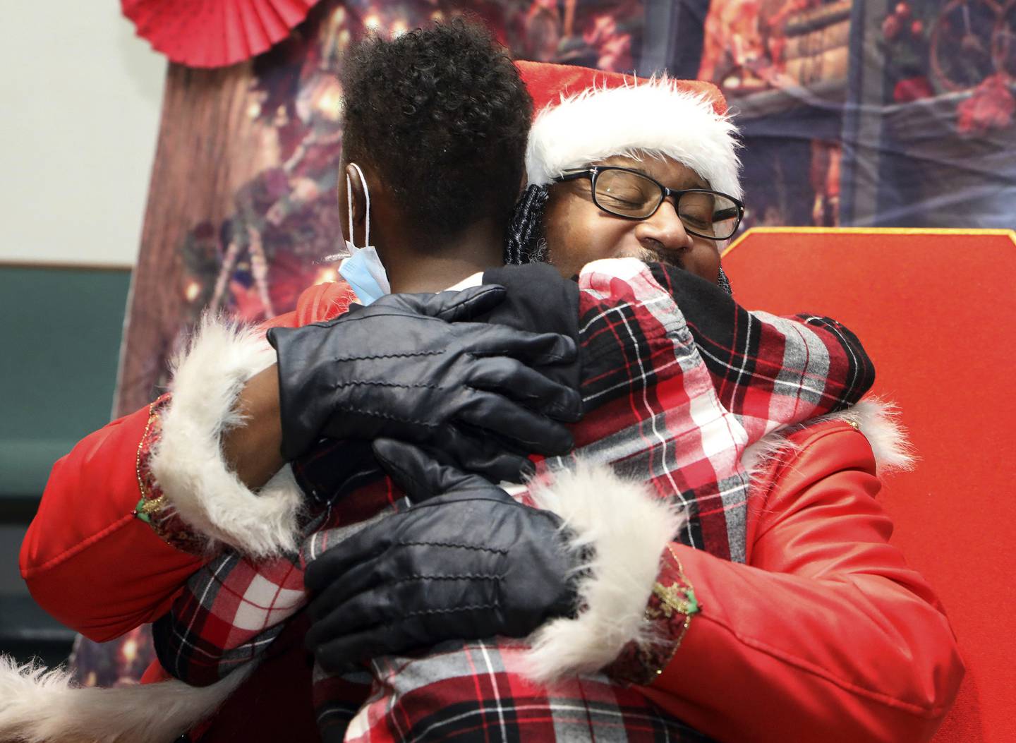 Andre Russell, as Dreezy Claus, hugs Jay'Sean Jordan during a visit to Rose of Light Church in Chicago on Dec. 17, 2022.