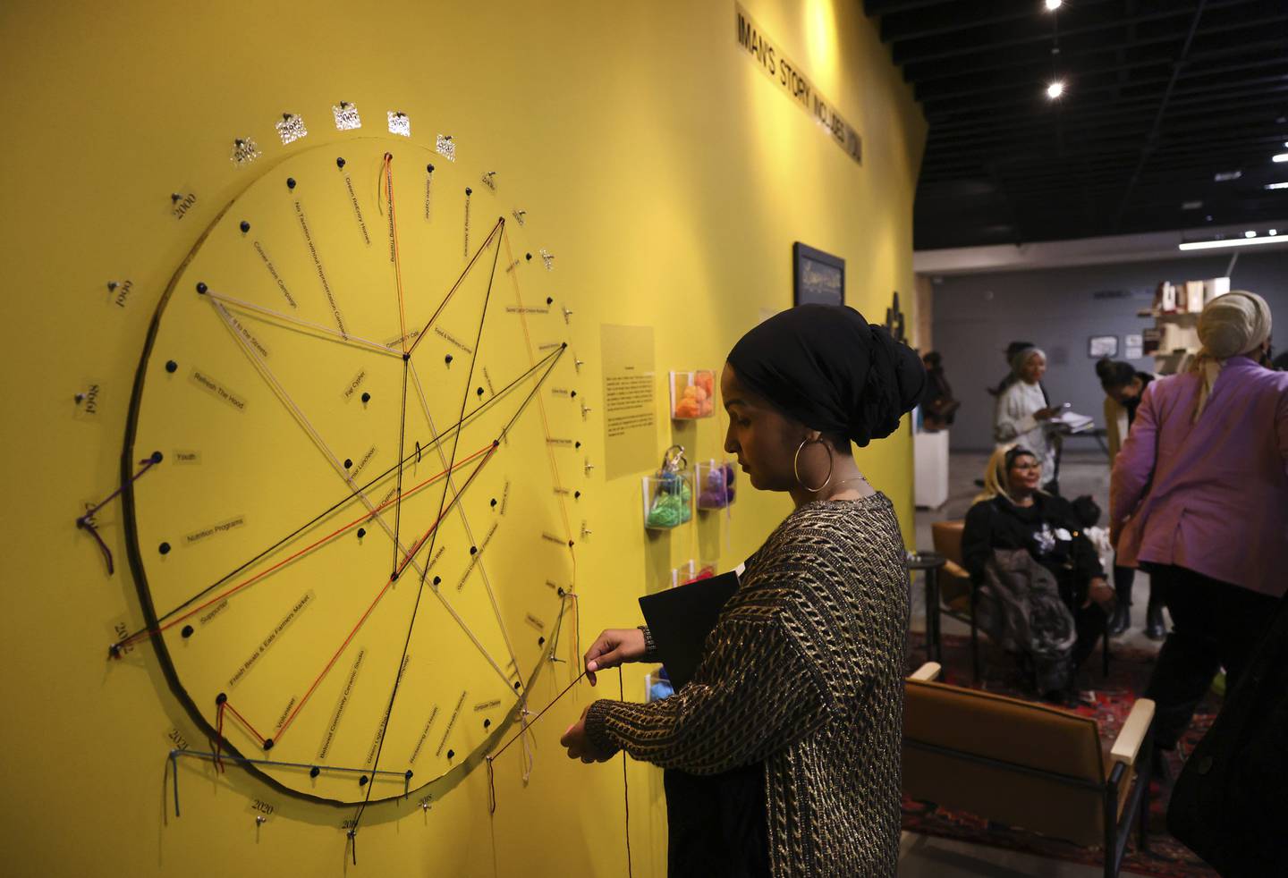 Samera Hadi uses yarn to connect her first experience to the year in which it occurred as she participates in an interactive piece at IMAN’s art gallery in the Chicago Lawn neighborhood of Chicago on Dec. 1, 2022. 