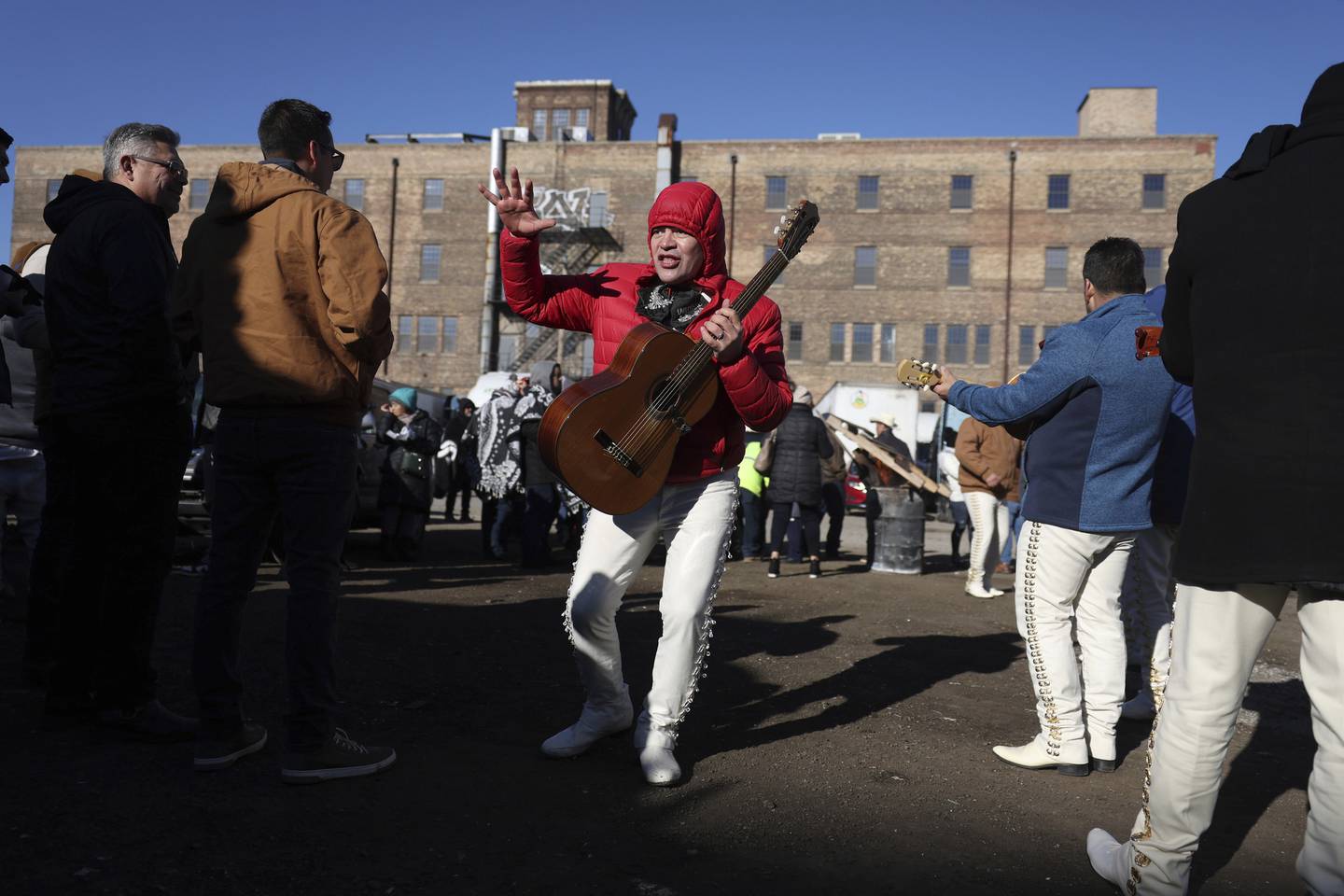 Javier Serna dances while playing guitar with a mariachi band near the truck caravan in the 1500 block of South Western Avenue on Dec. 3, 2022, in Chicago. 