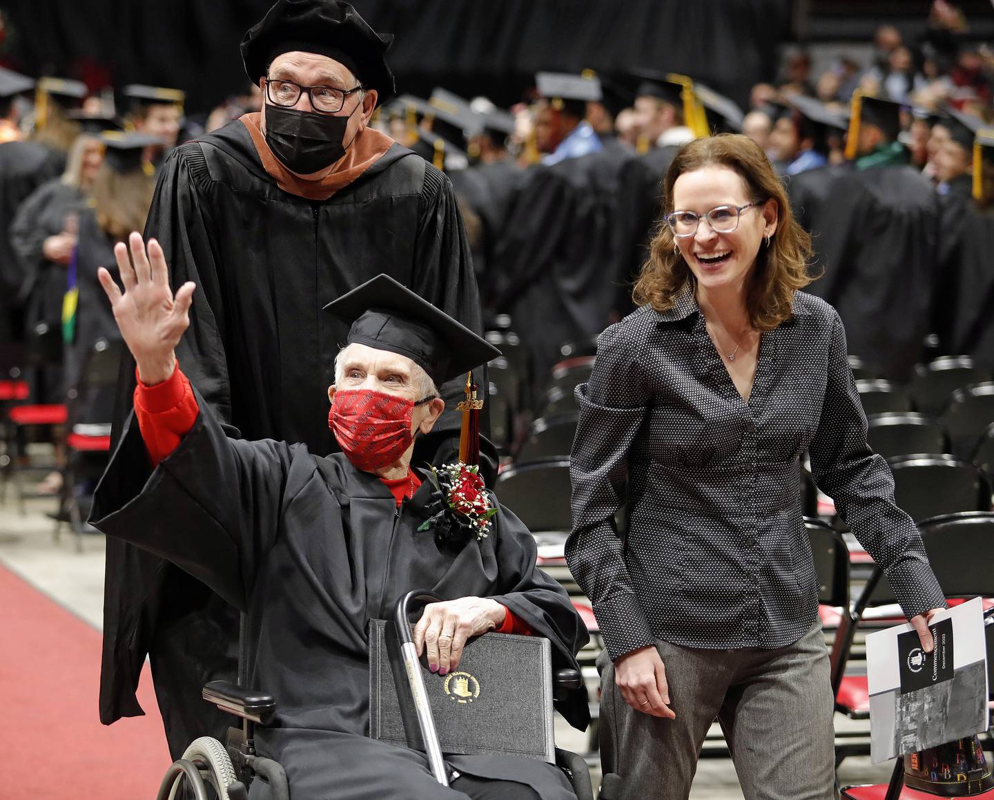 Graduate Joyce DeFauw, 90, waves to family as she is escorted by her granddaughter Jenna Dooley on Dec. 11, 2022.