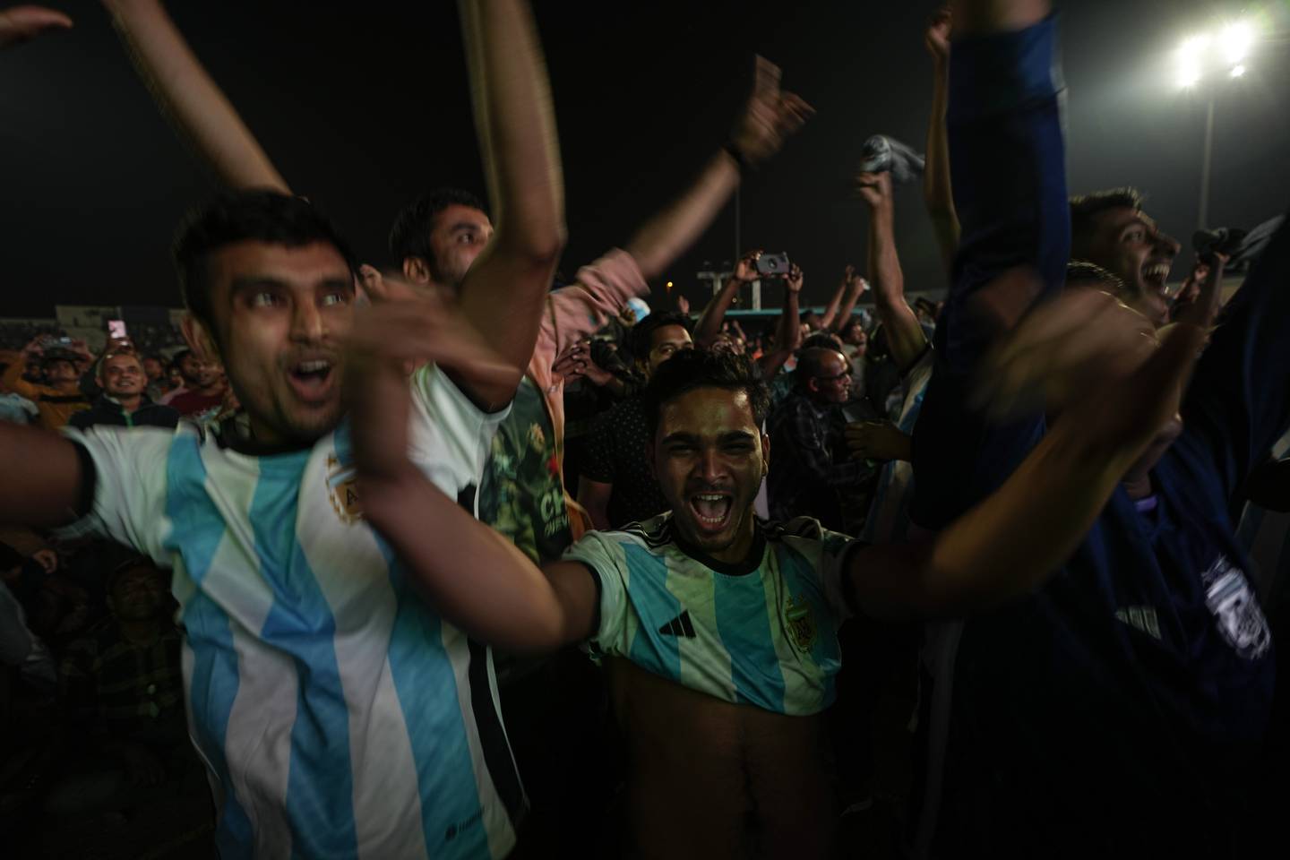 Migrant workers celebrate Argentina's Lionel Messi open goal in the World Cup round of 16 soccer match between Argentina and Australia as they watch on a big projection screen at the Asian Town Cricket Stadium in Doha, Qatar, on Dec. 3, 2022.  