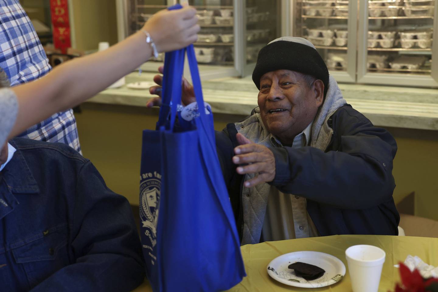 Ananias Flores, 78, smiles as he receives a gift bag at the Pilsen Satellite Senior Center at Casa Maravilla on Dec. 18, 2022, in Chicago. 