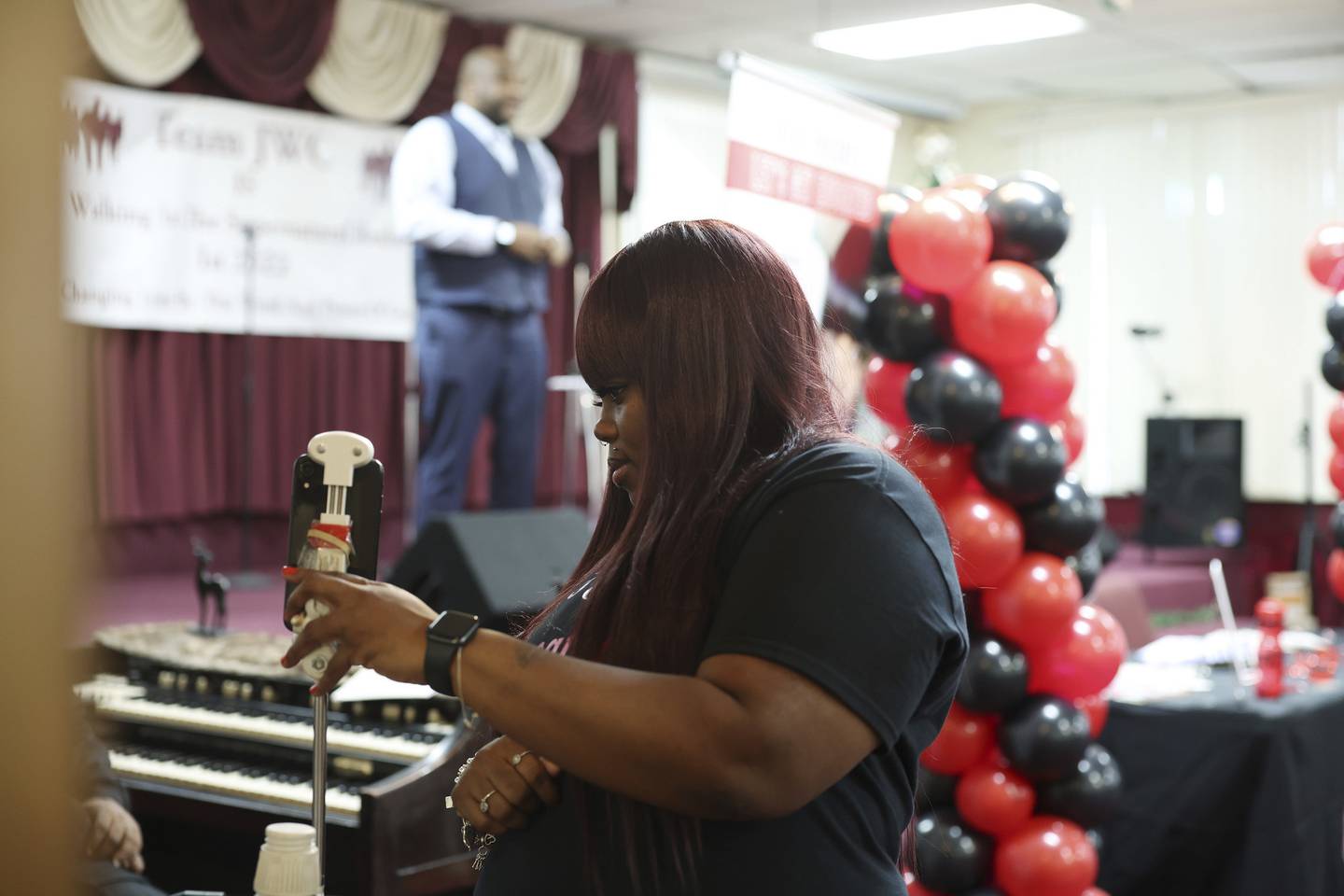 Chatrivia Kennedy sets up a live video feed with a smartphone as Jason Clanton of Howard Brown Health, in back, speaks at an event to bring awareness about people living with HIV on Dec. 10, 2022. 