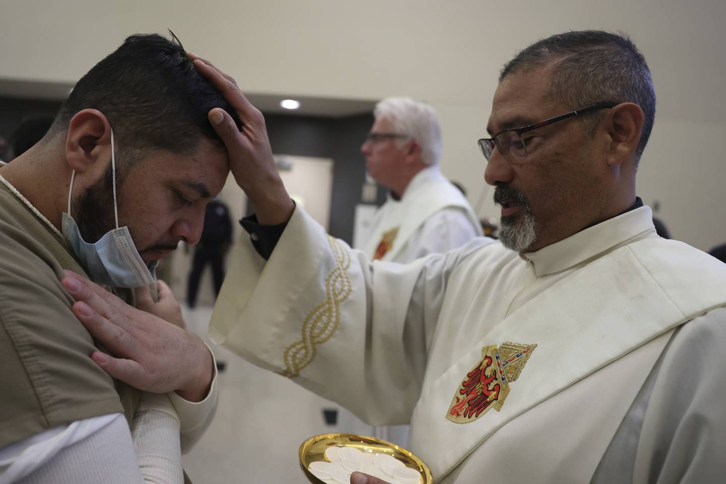 Deacon Pablo Perez gives out communion to an incarcerated individual during morning Christmas Mass at Cook County Jail on Sunday.