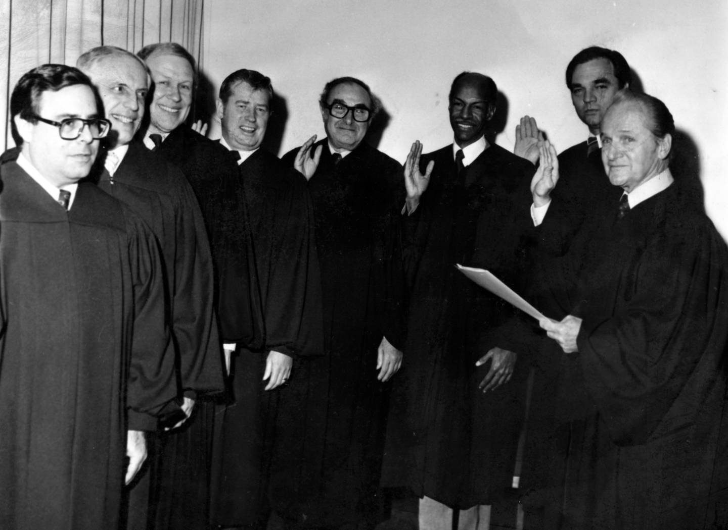 Chief Judge Harry G. Comerford, right, administers the oath of office to seven new associate judges in 1980, including Michael Toomin at far left. 