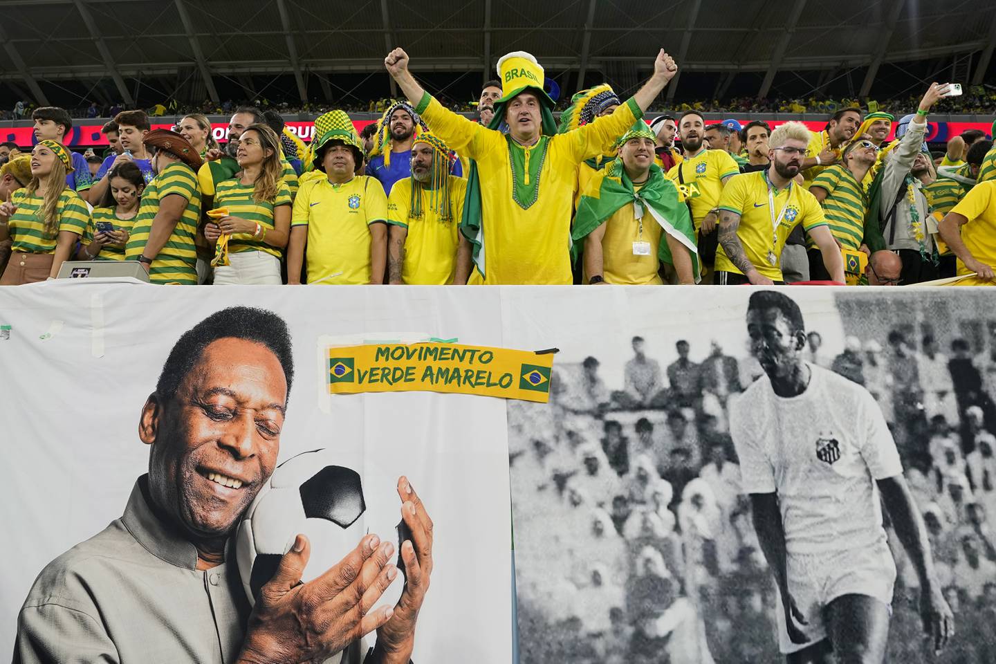 Brazil supporters cheer on the stands above a banner with pictures of soccer legend Pele while waiting for the start of a World Cup game on Dec. 5, 2022.