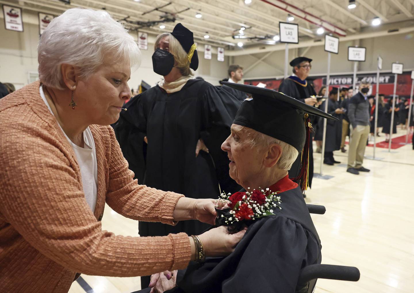 Joanne Wright adjusts flowers for her 90-year-old mother, Joyce DeFauw, before her commencement ceremony at Northern Illinois University on Dec. 11, 2022.