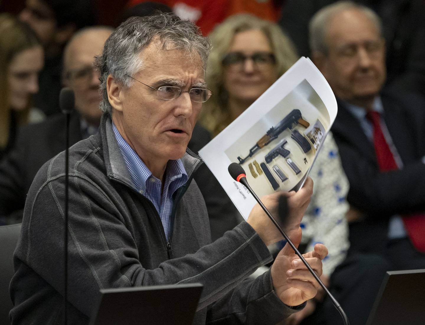 Cook County Sheriff Tom Dart holds photos of confiscated weapons while testifying, Dec. 20, 2022, during a hearing about gun legislation in front of an Illinois House committee in Chicago.