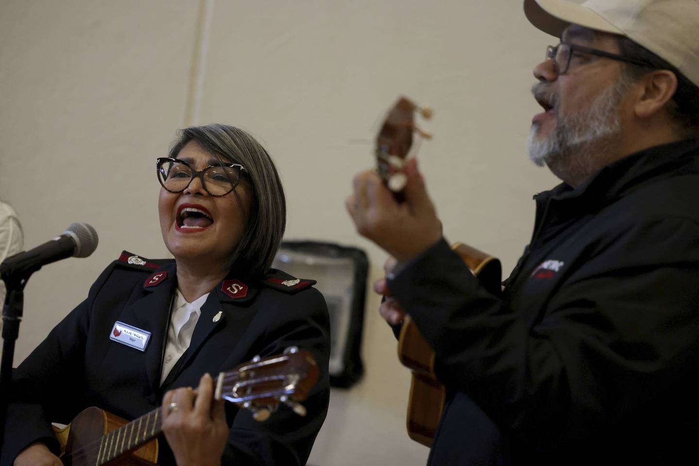 Nivia Paredes, left, and Daniel Paredes, both of the Salvation Army, sing at a holiday party for Venezuelan migrants hosted by the Salvation Army.